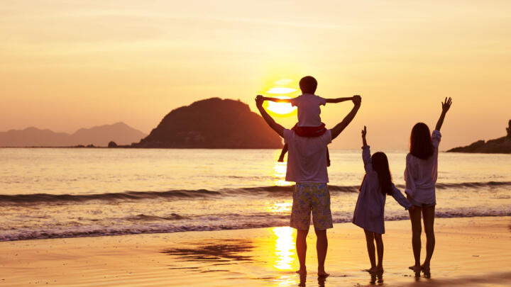Familie im Sonnenuntergang am Strand