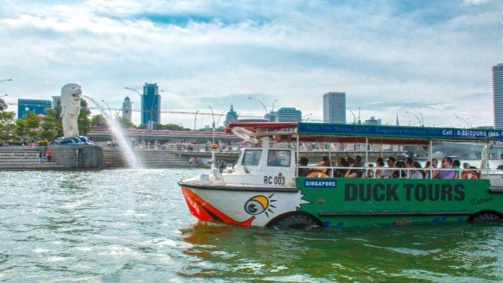 Amphibious Duck vehicle with painted face cruises past Merlion statue, Singapore