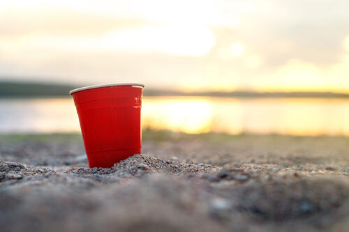 Beer pong cup on a beach with the ocean in the background