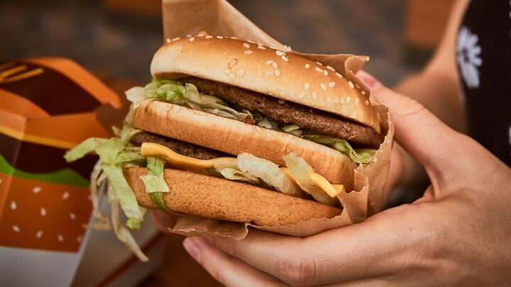 Person holding a double decker burger.