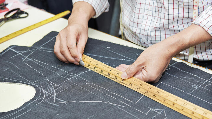Tailor measuring out a suit.
