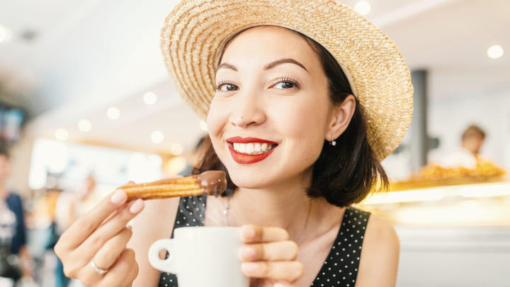 Woman eating churros con chocolate.