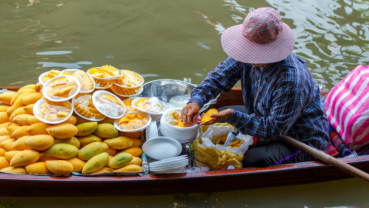 Hawker selling fresh mango and mango sticky rice from a longtail boat.