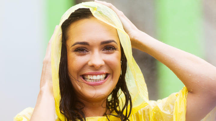 Woman wearing a rain poncho during a downpour.