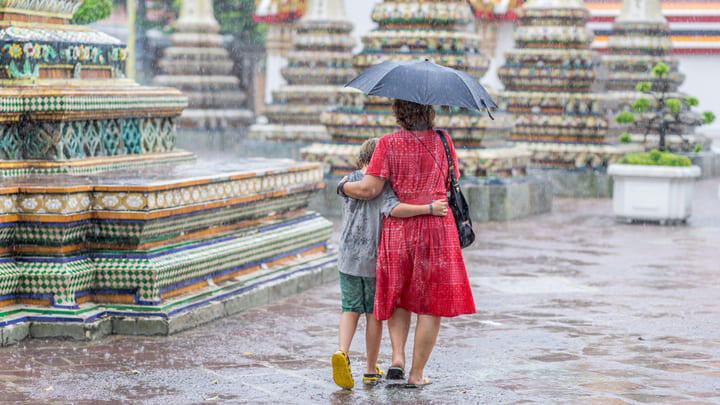 Woman and child walking in the rain at the Grand Palace in Bangkok.