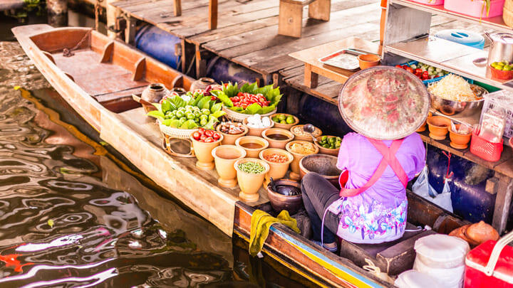 Fruit vendor in a longtail boat at Damnoen Saduak Floating Market, Bangkok.