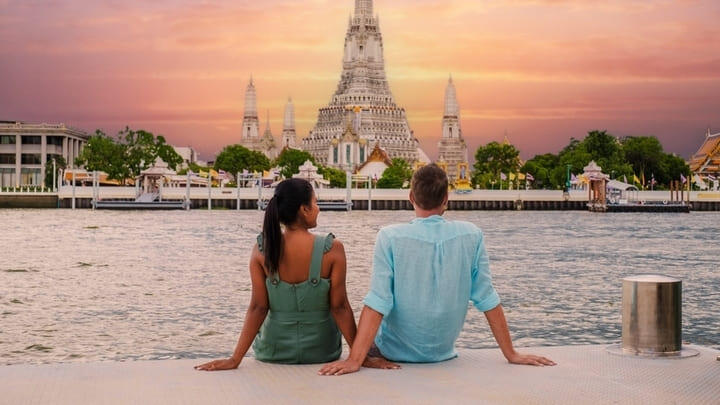 Couple enjoying sunset views of Wat Arun temple in Bangkok.