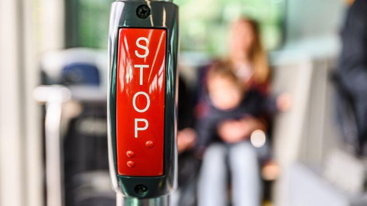 Close up of red Stop bell in bus, with background of blurred bus interior
