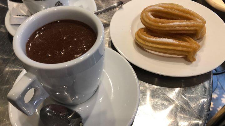 Close up of cup of hot chocolate and plate of churros on zinc table in La Boqueria, Barcelona