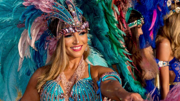 Close up of performer with enormous feathered headdress and sparkly top at Barcelona carnival