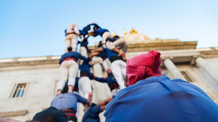 Onlooker in a red scarf watches castellers form a human tower in Barcelona