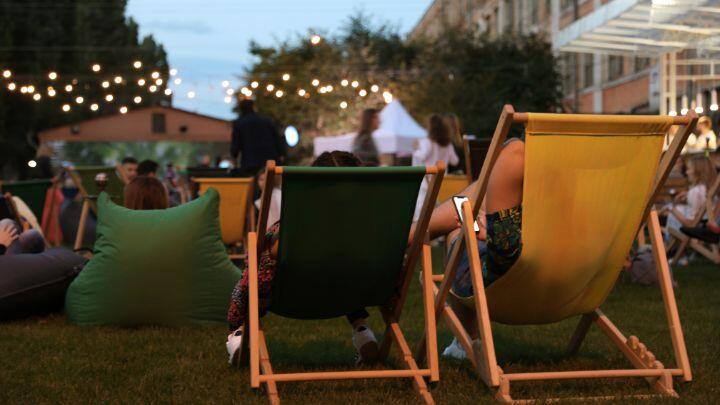 Green and yellow deckchairs seen from behind at outdoor concert with fairy lights