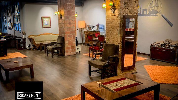 Furniture and stone pillars inside a room of Escape Hunt Barcelona + logo