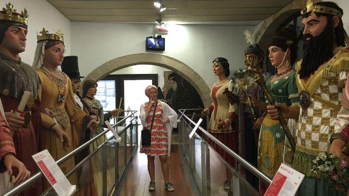 Woman stands on central walkway surrounded by giant papier mache figures at Giant Museum Barcelona