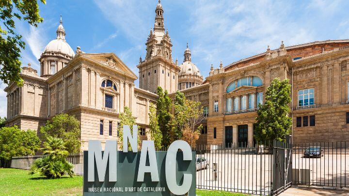 Exterior view of the Palau Nacional, with MNAC sign, with green lawn and blue sky