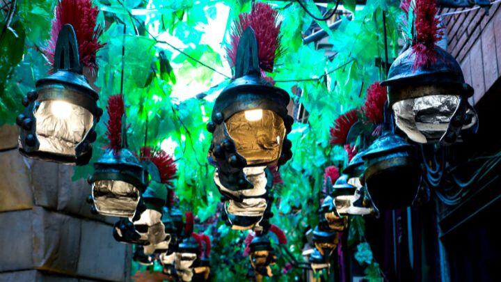 Roman helmet lanterns hang against green background in street decorated for Festa Major de Gracia, Barcelona