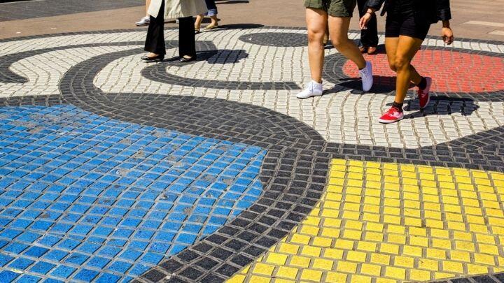 Feet walking over brightly coloured Miro mosaic on La Rambla, Barcelona
