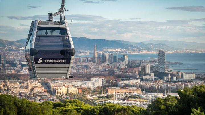 Teleferic de Montjuic cable car suspended over distant view of the city with Mediterranean sea beyond