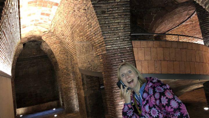 Excited woman leans into shot of brick architectural shapes in basement of Palau Guell