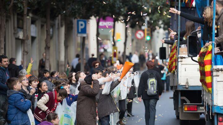Streetside crowds hold out paper cones and bags to catch sweets thrown from carnival floats