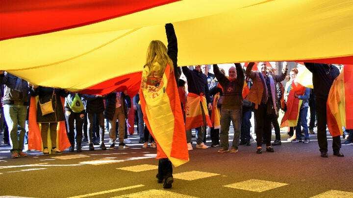 A woman holding up a giant Spanish flag during a Constitution Day procession