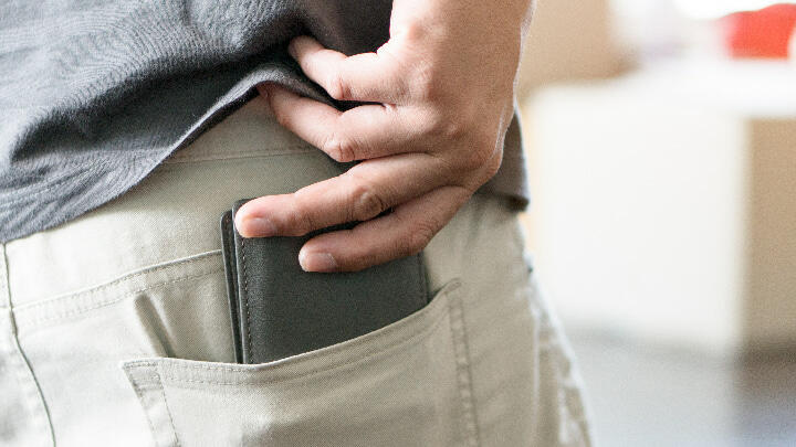 A man removing his wallet from his back trouser pocket
