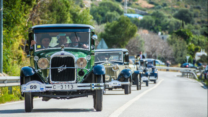 A procession of vintage automobiles driving along a Barcelona road