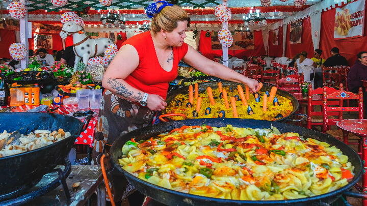 A woman preparing various pots of food at a Barcelona April fair stall