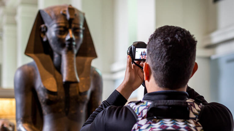 A tourist photographs a statue at the British Museum